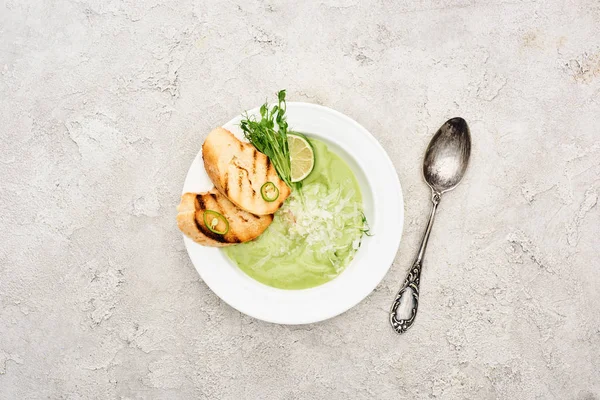スプーンで出されるクルトンとおいしいクリーミーな緑の野菜スープのトップビュー — ストック写真