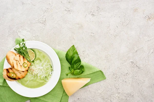 Top view of delicious creamy green vegetable soup with croutons served on napkin near spinach leaves and cheese — Stock Image Top View Delicious Creamy Green Vegetable Soup Croutons Served Napkin Royalty Free Stock Images