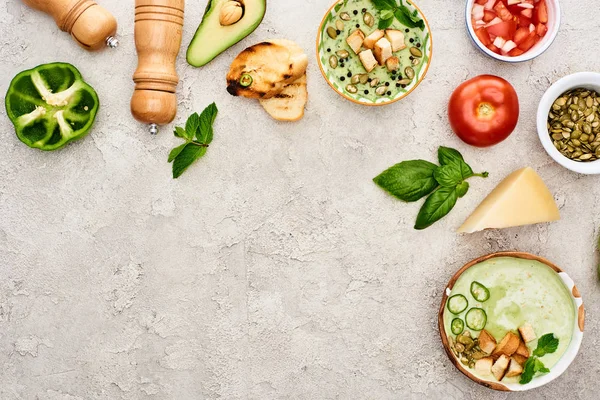 Top view of delicious creamy green vegetable soup in bowls near fresh vegetables on textured surface — Stock Image Top View Delicious Creamy Green Vegetable Soup Bowls Fresh Vegetables Royalty Free Stock Photos