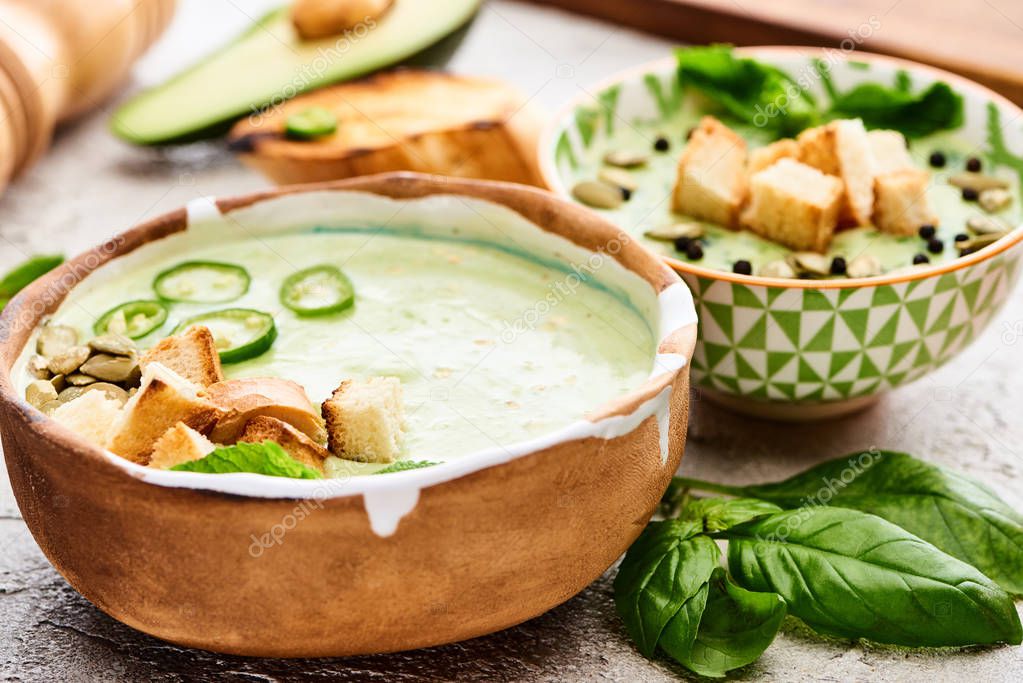 bowls with delicious green vegetable creamy soup with croutons