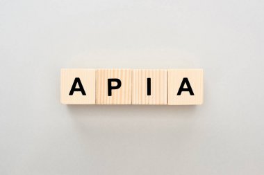 top view of wooden blocks with Apia lettering on grey background clipart