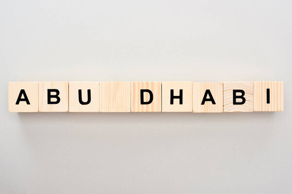 top view of wooden blocks with Abu Dhabi lettering on grey background