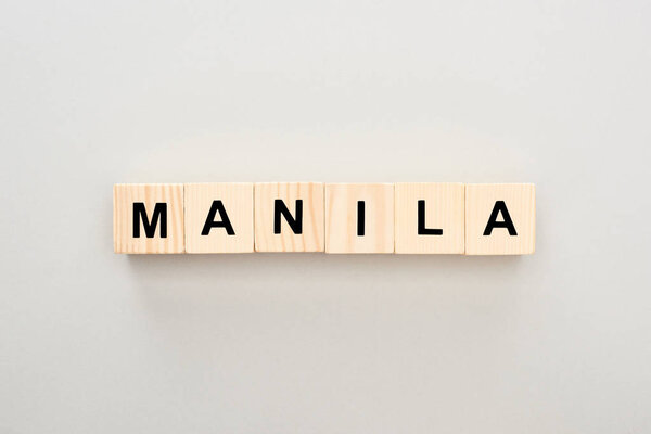 вид сверху на деревянные блоки с надписью Манила на сером фоне
