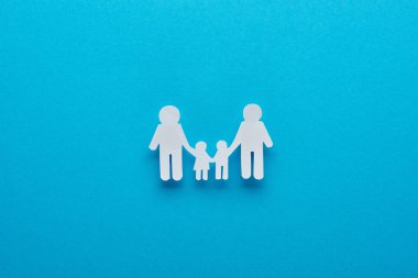 mavi arka plan üzerinde el ele kağıt kesim aile üst görünümü