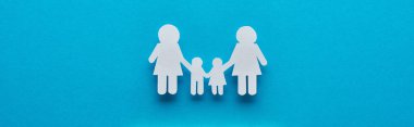 top view of paper cut lesbian family holding hands on blue background, panoramic shot clipart