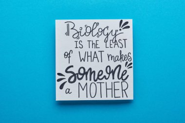 top view of card with biology is least of what makes someone mother lettering on blue background clipart
