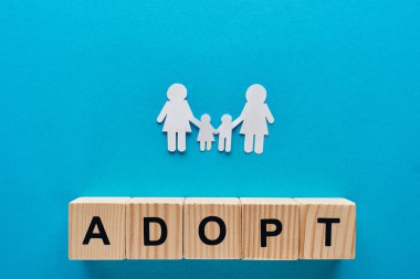 ahşap küpler üzerinde yazı benimseyen mavi arka plan üzerinde el ele veren kağıt kesim lezbiyen aile üst görünümü