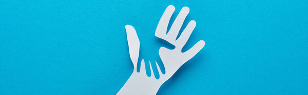 top view of paper cut parent and child hands on blue background, panoramic shot