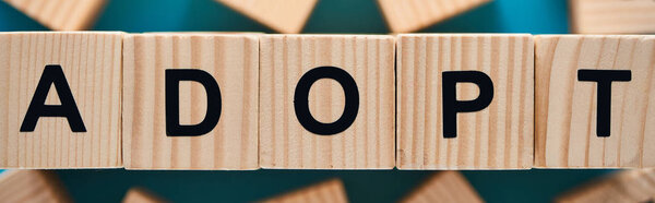 selective focus of adopt word made of wooden cubes, panoramic shot
