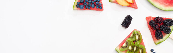 panoramic shot of organic watermelon on sticks with seasonal berries and fruits on white background