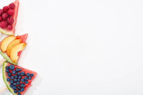 top view of delicious watermelon on sticks with seasonal berries and nectarine on white background with copy space