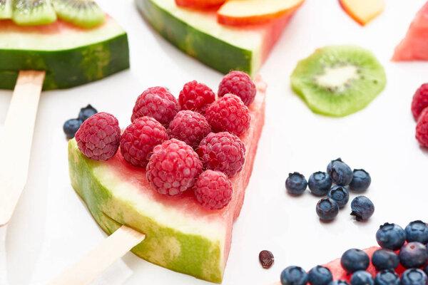 close up view of delicious dessert with watermelon on stick and raspberries on white background