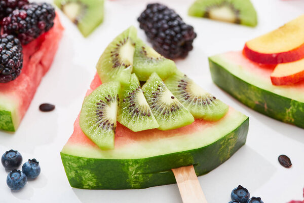 close up view of delicious dessert with watermelon on stick and kiwi on white background