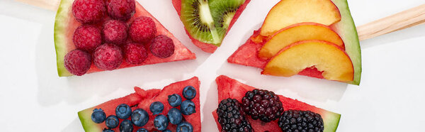 panoramic shot of delicious dessert with watermelon on sticks and berries on white background