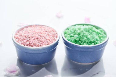 pembe yaprakları ile beyaz yüzeyüzerinde banyo tuzları ile mavi bardak yakın görünümü