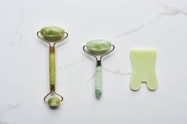 top view of jadeite facial rollers and spatula on marble surface clipart