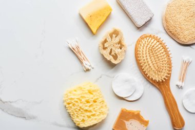 mermer yüzeyde saç fırçası, pamuklu bezler ve pedler, pomza taşı ve banyo süngeri üst görünümü
