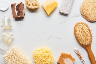 mermer yüzeyinde masaj kavanoz, saç fırçası, banyo süngeri, loofah ve pomza taşı üst görünümü