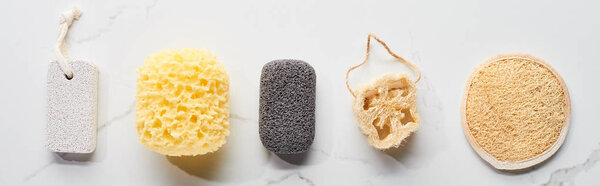 panoramic shot of bath sponges and pumice stones on marble surface