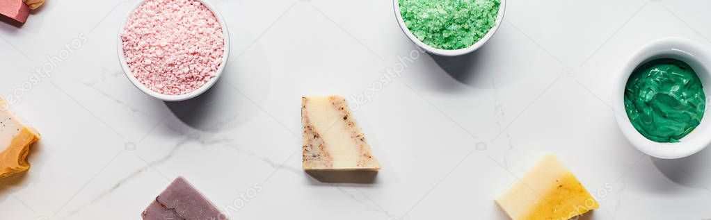 panoramic shot of cups with natural beauty products and soap on marble surface