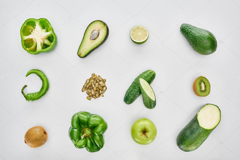 top view of apple, avocados, cucumbers, lime, peppers, pumpkin seeds and zucchini