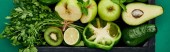 panoramic shot of apples, avocados, pepper, kiwi, greenery, lime in wooden box