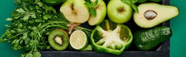 panoramic shot of apples, avocados, pepper, kiwi, greenery, lime in wooden box clipart
