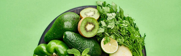panoramic shot of avocados, kiwi, lime, pepper and greenery on pizza skillet 
