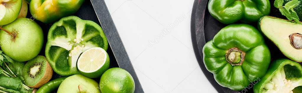 panoramic shot of fresh kiwi, limes, peppers, apples, avocado in wooden box and pizza pan