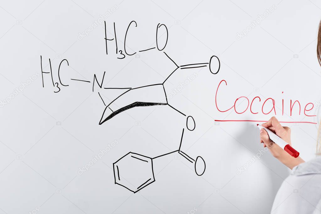 cropped view of woman writing cocaine on white board 