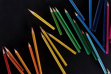 Scattered sharpened color pencils isolated on black clipart