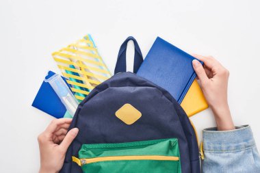 Blue schoolbag with notepad and pencil case in hands of schoolgirl isolated on white clipart