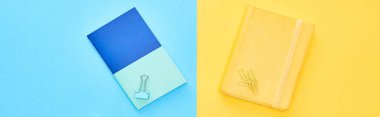 Panoramic shot of blue and yellow notepads on bicolor background clipart