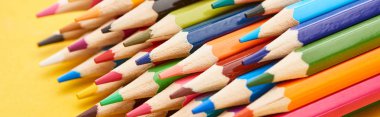 Sharpened ends of color pencils on yellow background clipart
