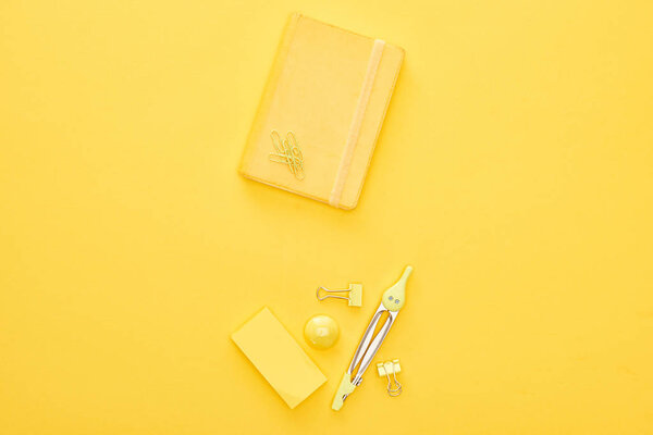 Top view of yellow notepad and stationery on same background