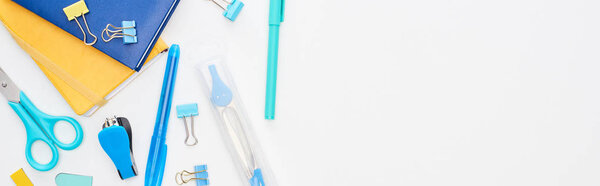 Панорамный снимок синих и желтых разбросанных школьных принадлежностей, изолированных на белом
