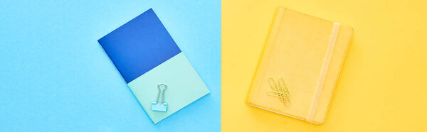 Панорамный снимок синих и желтых блокнотов на двухцветном фоне
