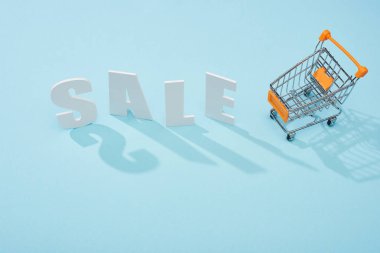 mavi arka plan üzerinde alışveriş arabası yakınında beyaz satış yazı üst görünümü