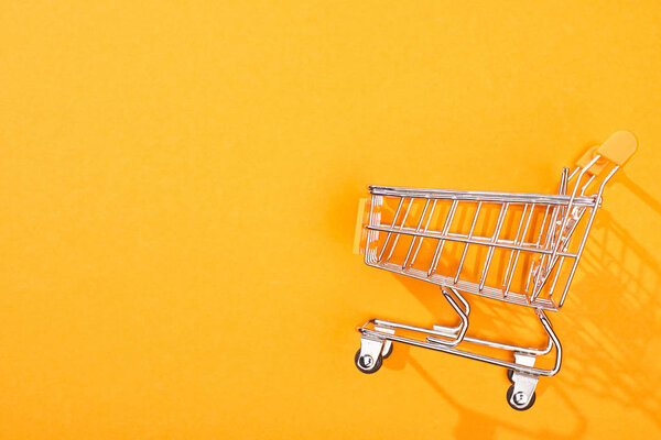top view of empty shopping cart on bright orange background