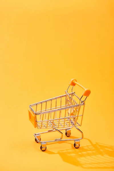 明亮的橙色背景上的空小购物车 — 图库照片