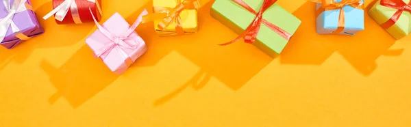 明るいオレンジ色の背景に祝いの包まれた贈り物のトップビュー パノラマショット — ストック写真