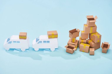 white mini vans near pile of cardboard boxes on blue background clipart