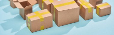 panoramic shot of cardboard postal boxes on blue background clipart
