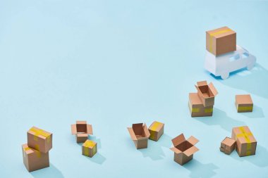 kopya alanı ile mavi arka plan üzerinde mini kamyon yakınında dağınık karton kutular