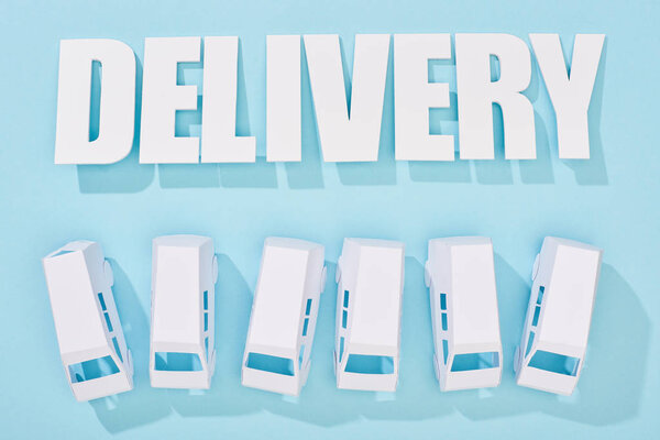 delivery inscription with shadows near mini vans on blue background