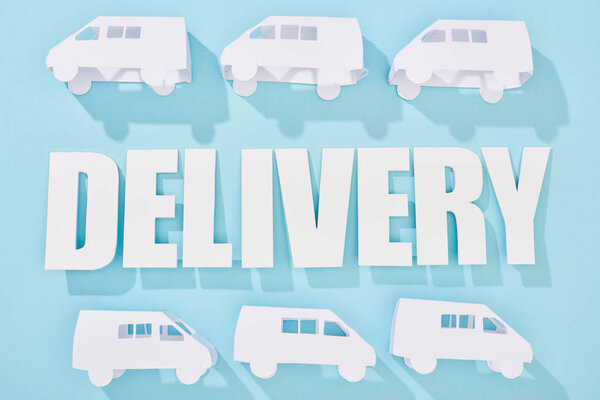 white mini vans around delivery inscription with shadows near blue background