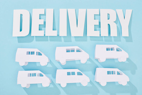 white mini vans behind delivery inscription with shadows near blue background