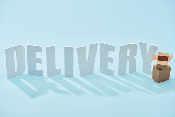 cardboard boxes one on each other near white delivery inscription on blue background 