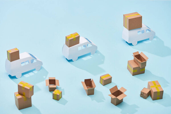 белые минивэны с закрытыми картонными посылками рядом с коробками на синем фоне
