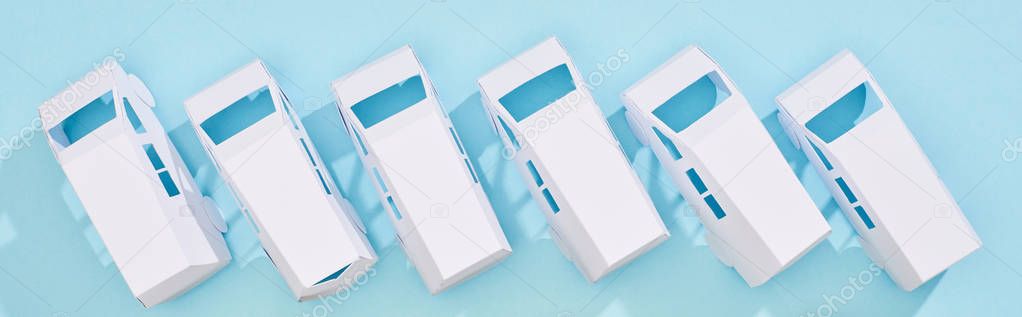 panoramic shot of miniature white autos on blue background